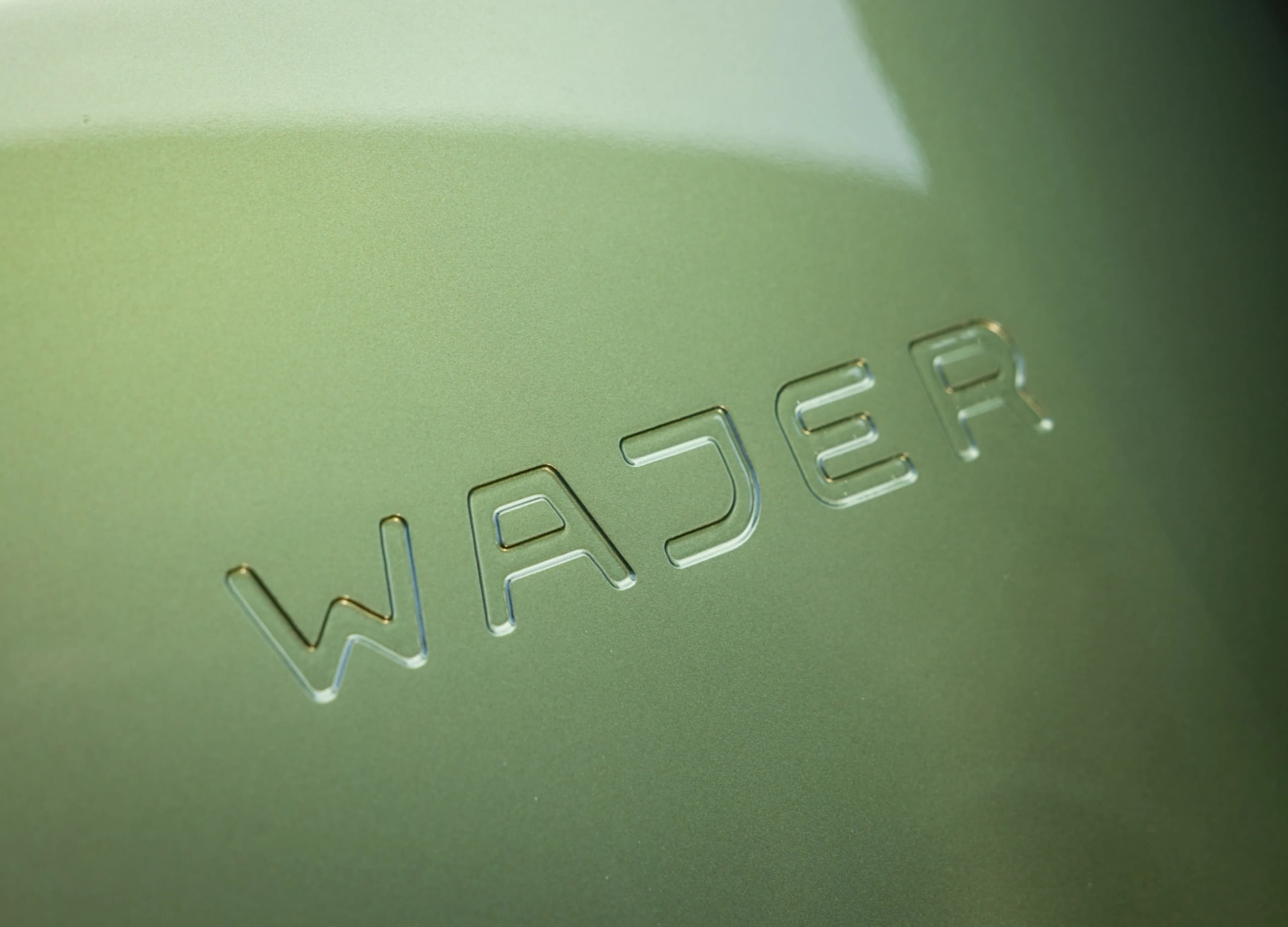 Close-up of embossed "Wajer" text on a smooth, light green surface.
